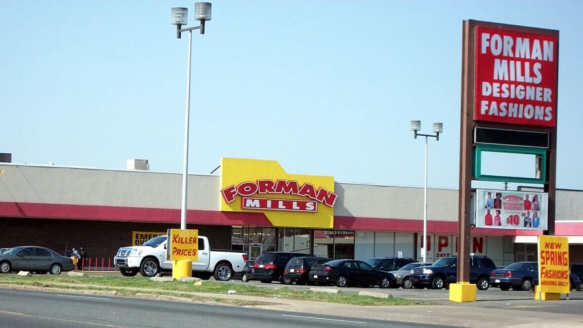 A store at a strip mall with a bright yellow and red storefront. A big red sign with white block letters on the left.