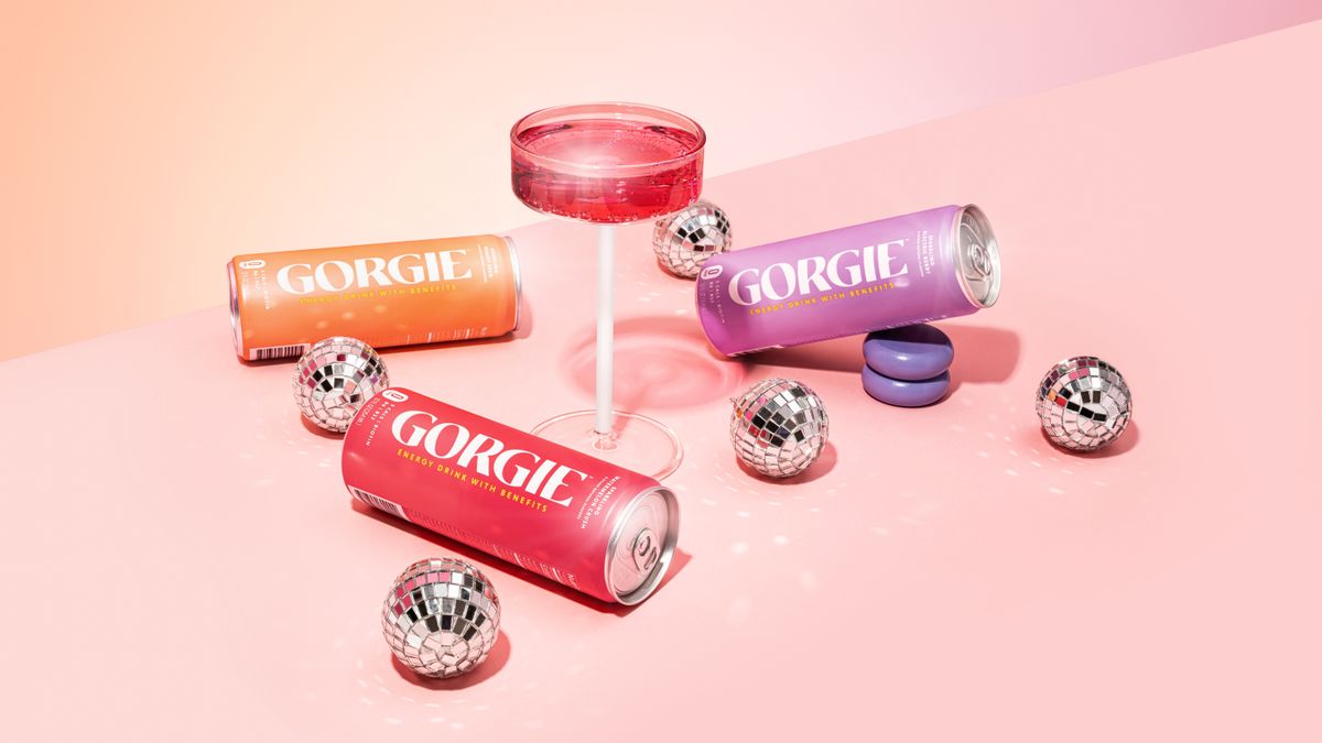 Three pink Gorgie energy drink cans displayed with a pink martini glass