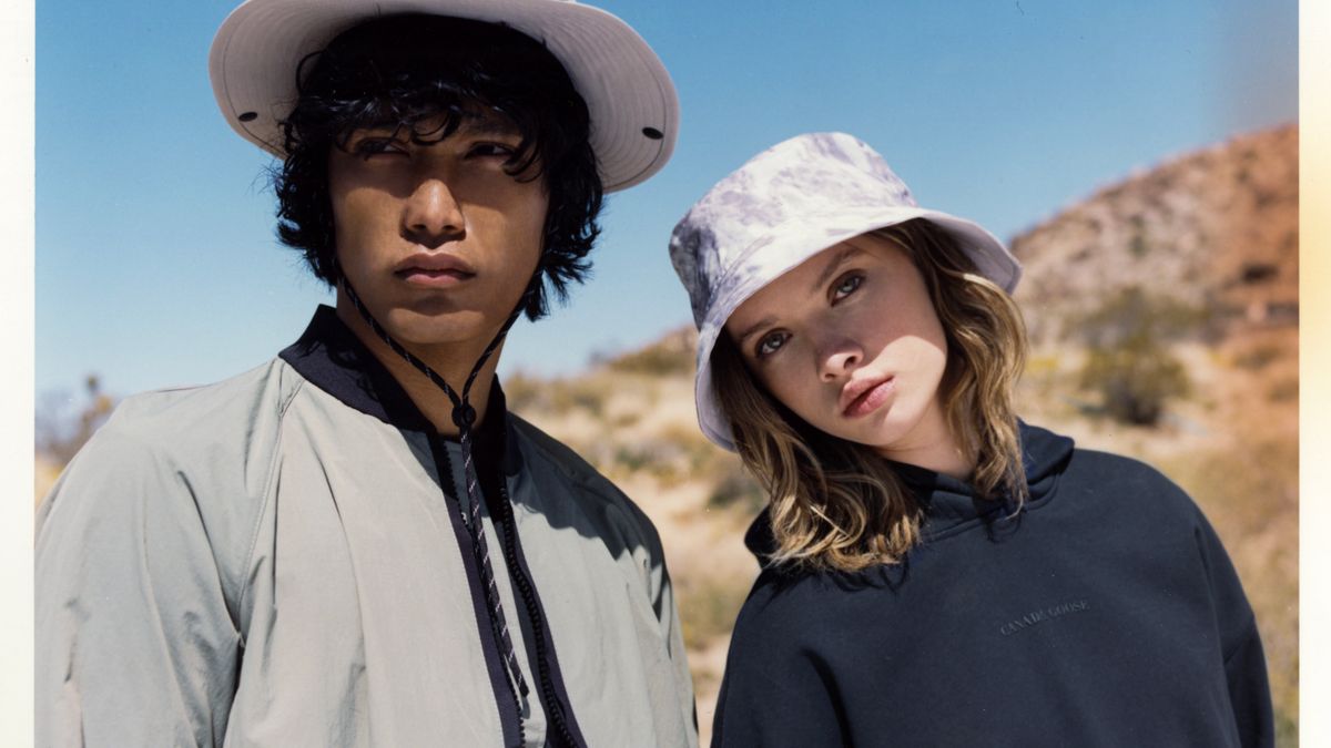Two models with light colored hats and dark hair pose