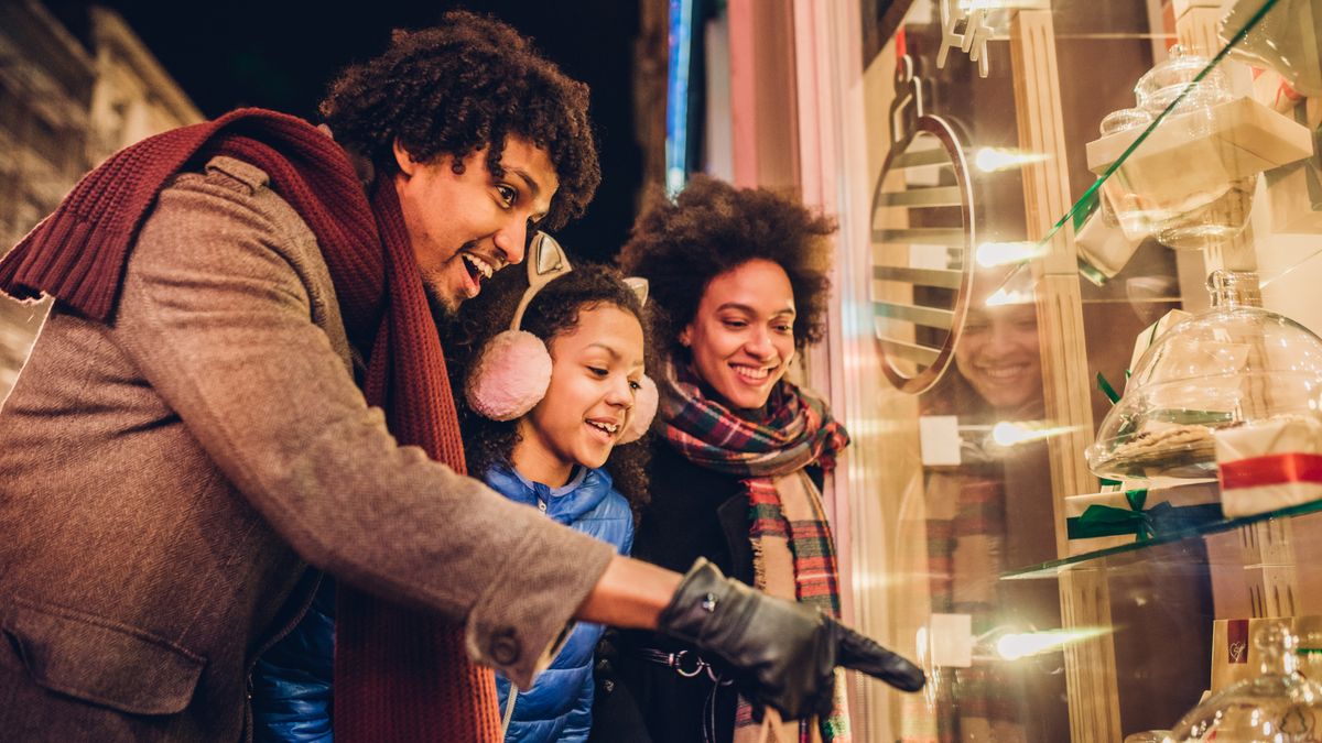 Smiling young family looking at candy and Christmas presents in a store window.