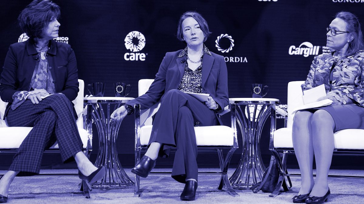 Three business woman discuss on stage.