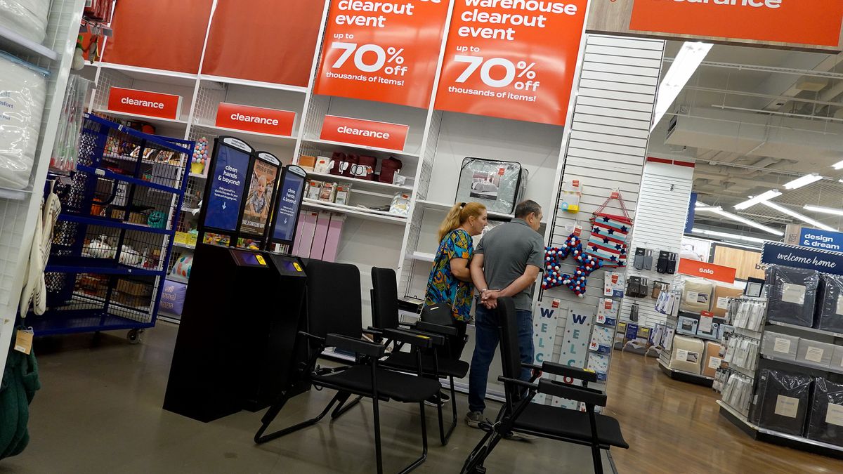 Image of customers shopping in a Bed Bath & Beyond store with sale signs visible.