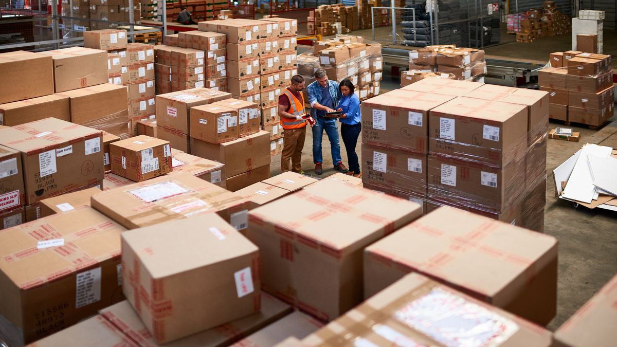 People at work in a large warehouse full of boxes.