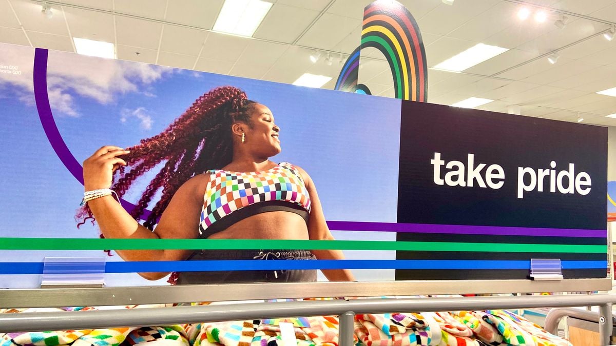 A store display shows a person looking off to the side and tossing their hair, and the words "take pride."