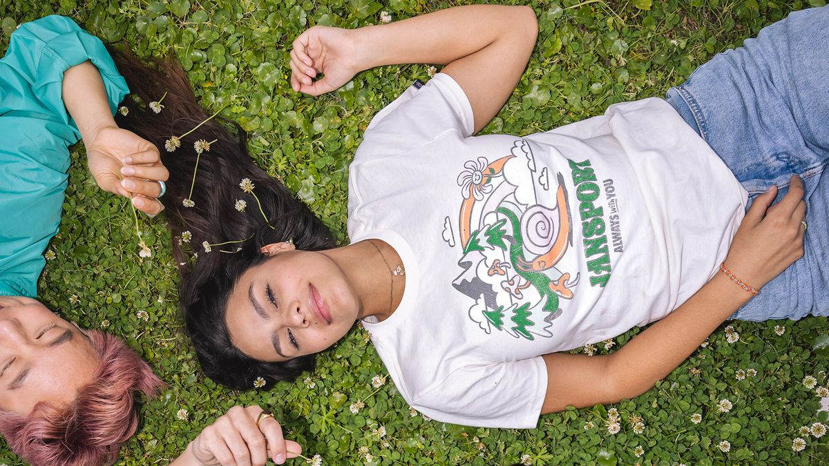 Young people lying on the grass holding little white flowers.