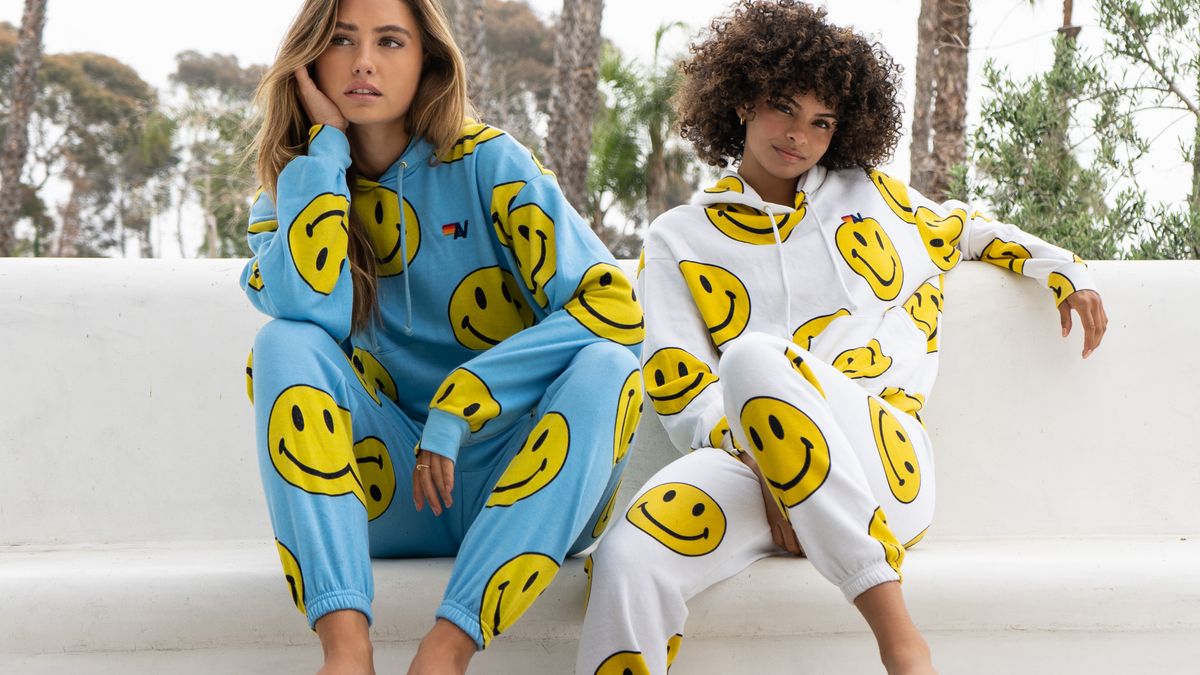 Two people pose on a set of steps in smiley face outfits.