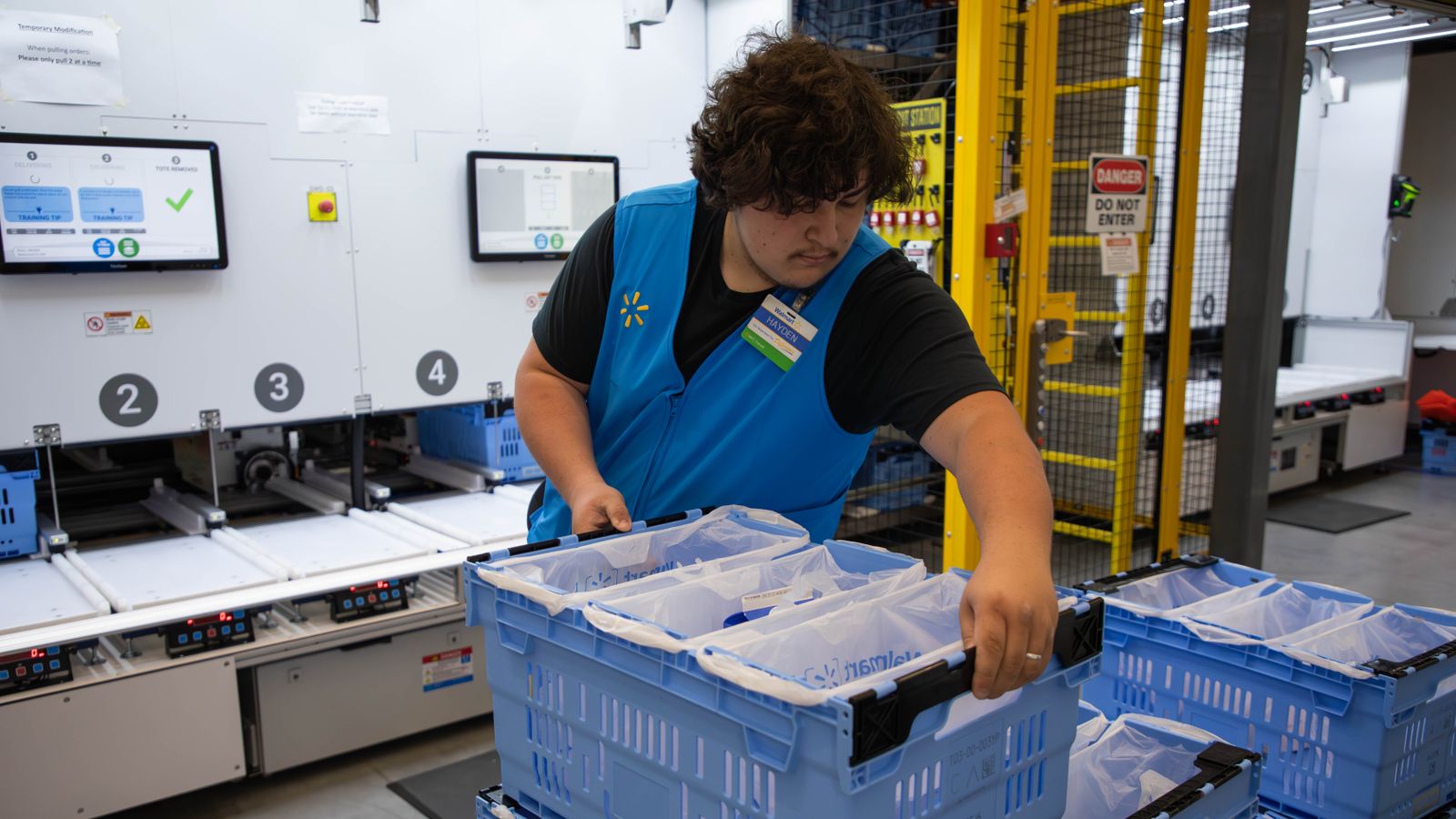 A Walmart employee handles a crate in a market fulfillment center.